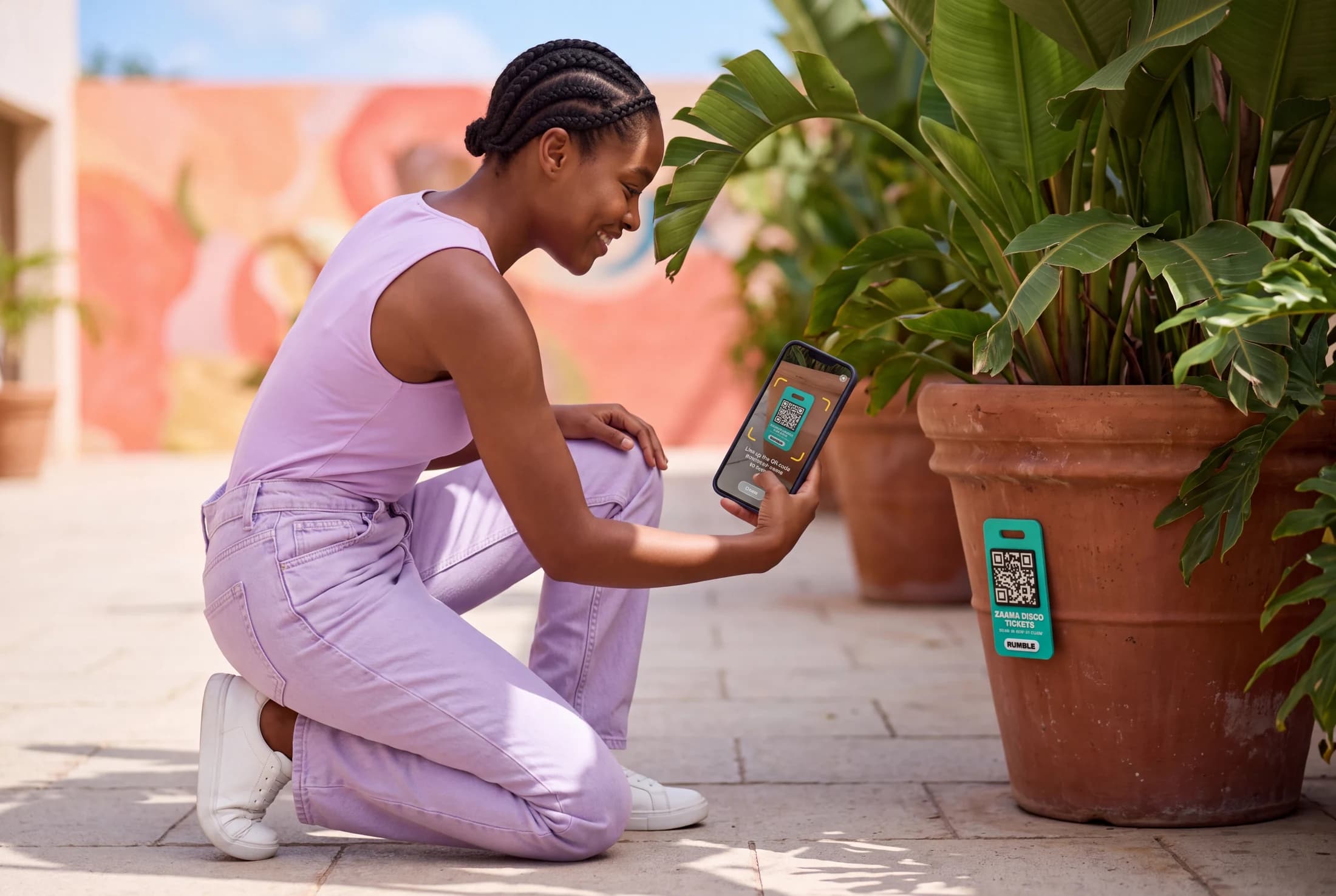 A player kneels beside a courtyard planter to scan a teal Rumble prize tag.